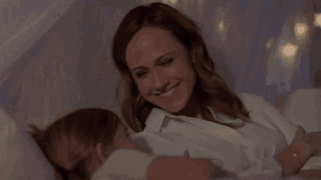 a woman is kneeling on a bed with a child .