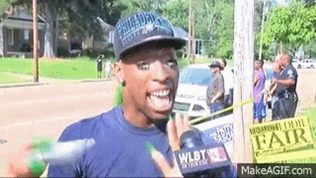 a man wearing a hat is talking into a microphone while holding a water gun .