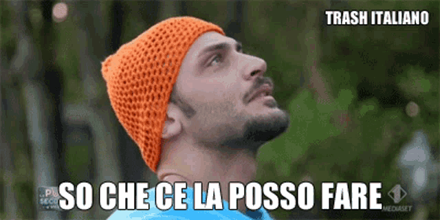 a man wearing an orange knitted hat is looking up with the words so che ce la posso fare written below him