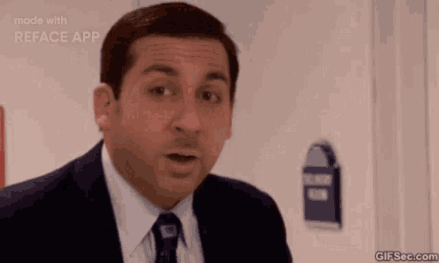 a man in a suit and tie is making a funny face while standing in front of a door .