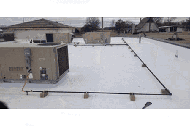 an air conditioner is sitting on top of a white roof next to a house