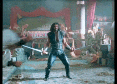 a man is holding a sword in a room in a movie scene .