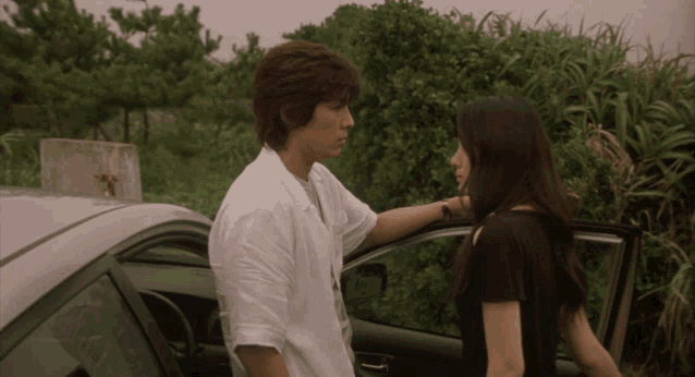 a man and woman standing next to a car