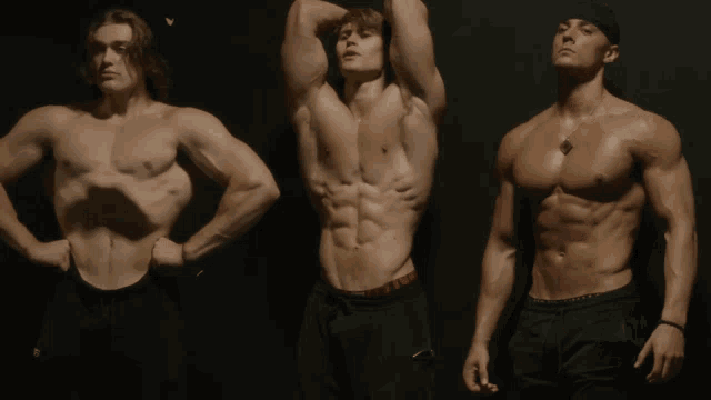 three muscular men are standing next to each other with one wearing a red under armour brief