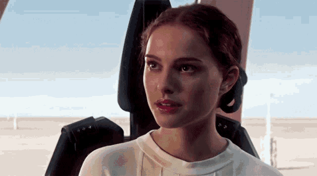 a woman in a white shirt is sitting in a chair looking out the window .