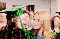 a woman in a green graduation cap and gown stands next to another woman