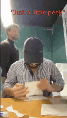 a man sitting at a table with the words just a little peek