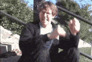 a man in a black jacket is sitting on a set of stairs with his arms outstretched