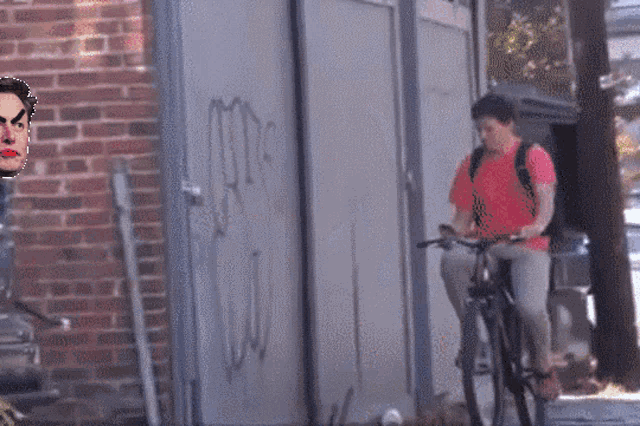 a man is riding a bike in front of a brick wall with graffiti on it that says mrs.