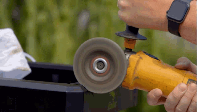 a person wearing a smart watch is using a grinder on a piece of metal