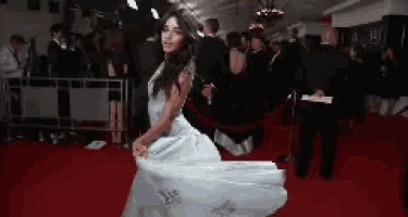 a woman in a white dress is dancing on the red carpet