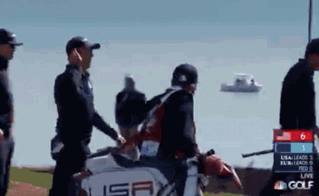 a group of people are walking on a golf course with a scoreboard that says nbc golf
