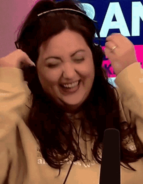 a woman wearing headphones is laughing in front of a sign that says " am "
