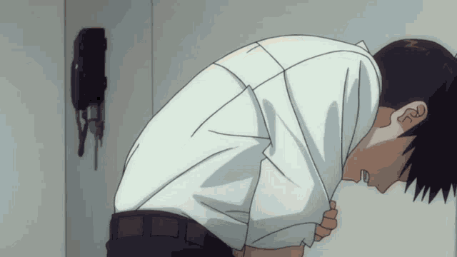 a man in a white shirt is kneeling down in front of a wall