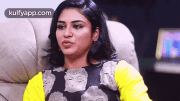 a woman is sitting on a couch with her eyes closed and a yellow top on .