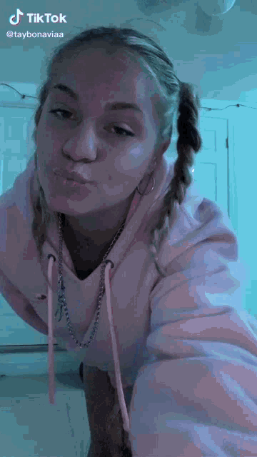 a woman in a pink hoodie is making a funny face and has a tiktok account