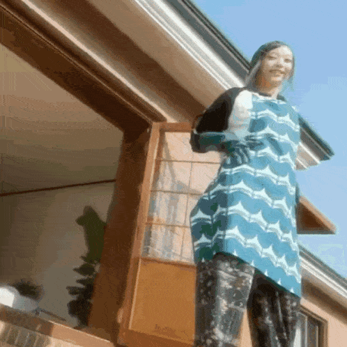 a woman wearing an apron and gloves stands on a balcony
