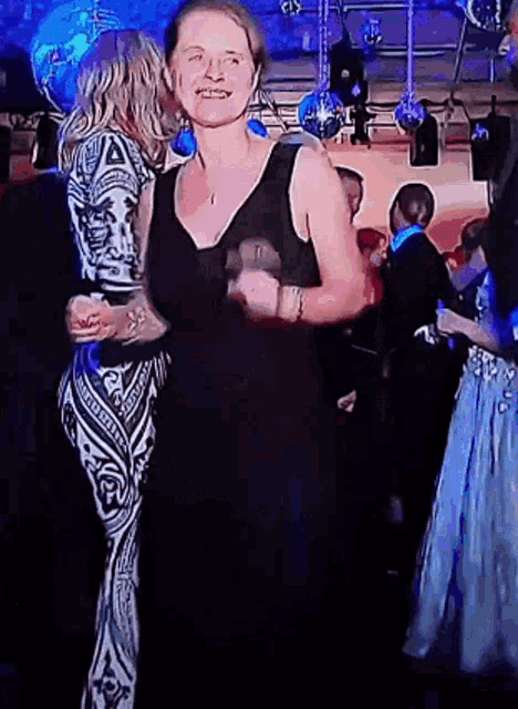 a woman in a black dress is dancing with another woman