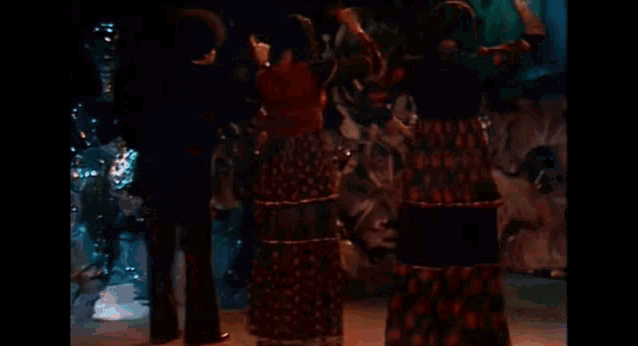 a man in a tuxedo and a woman in a dress are dancing in a dark room .