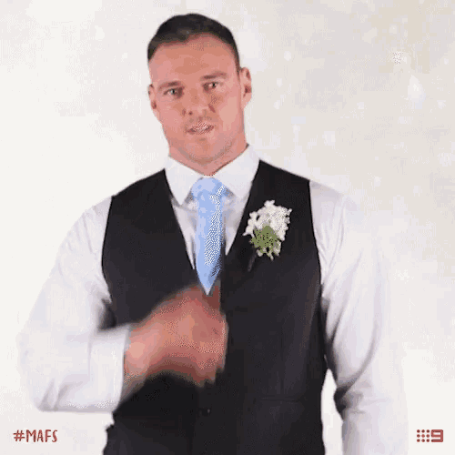 a man in a suit with a blue tie and a flower in his lapel