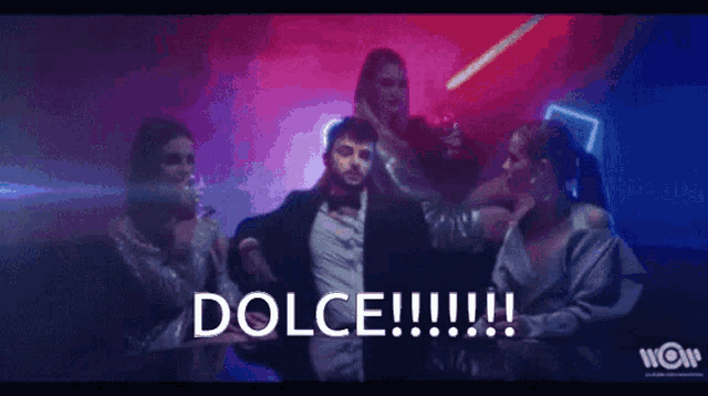 a man in a suit and bow tie is dancing in front of a group of people and the word dolce is visible