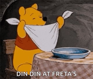 a cartoon of winnie the pooh sitting at a table holding a towel around his neck .