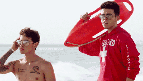 a man in a red lifeguard sweatshirt stands next to another man