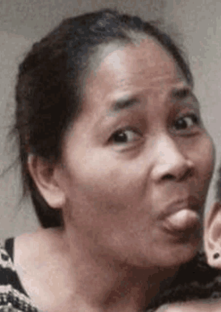 a woman is making a funny face with her tongue out while holding a baby .