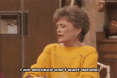 a woman in a yellow sweater is sitting at a table saying `` i am shocked and i want details ! ''