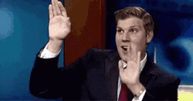 a man in a suit and tie is making a funny face while waving his hand .