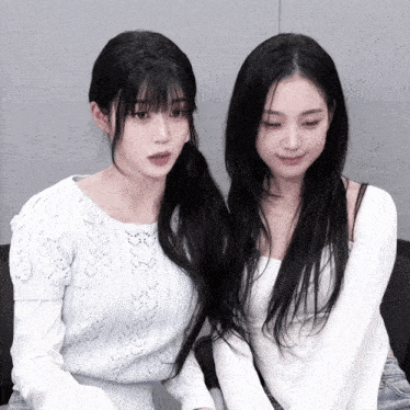 two girls are sitting next to each other and one is wearing a blue sweater