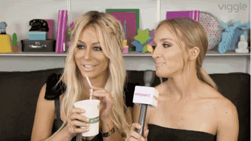 two women are drinking through a straw and one has a microphone that says viggle