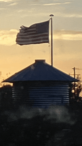a broken american flag is flying in the wind above a building