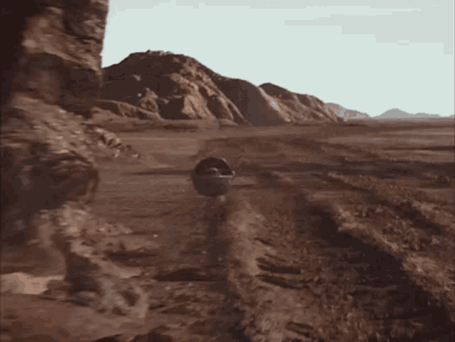 a baby in a stroller is walking across a dirt road