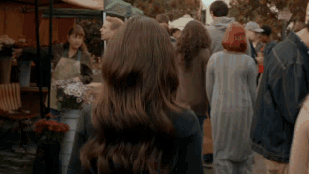 a woman with long brown hair stands in a crowd