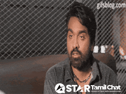 a man with a beard is sitting in front of a fence with a star tamil chat logo in the corner