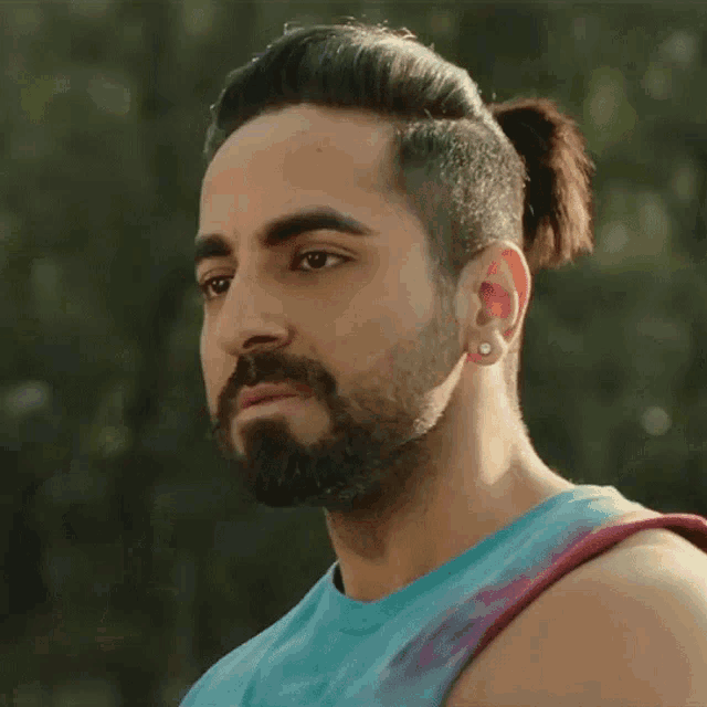 a man with a beard is wearing a blue tank top