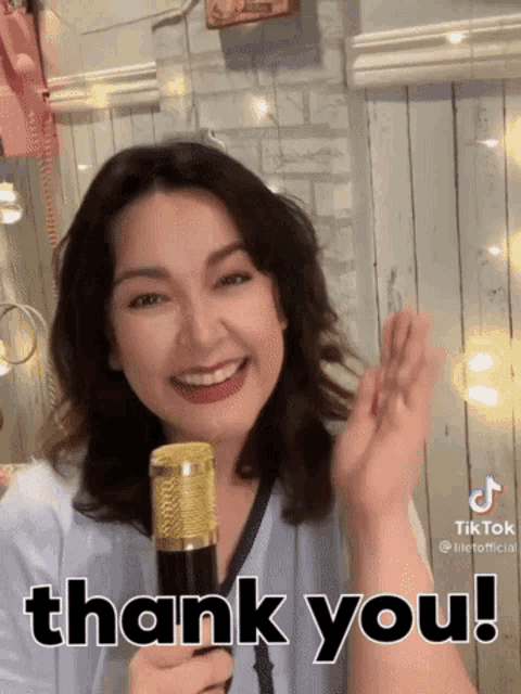 a woman holding a microphone with the words thank you written on it