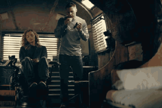 a man is holding a gun while a woman sits in a wheelchair looks on