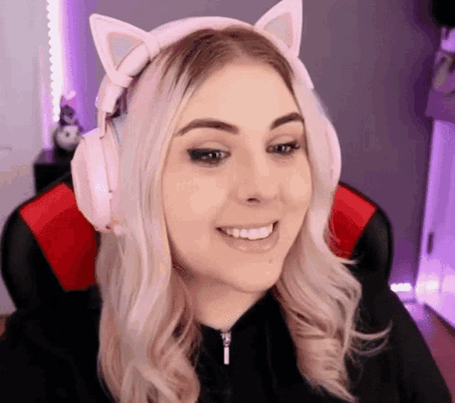 a woman is wearing a pair of pink cat ears headphones and smiling .