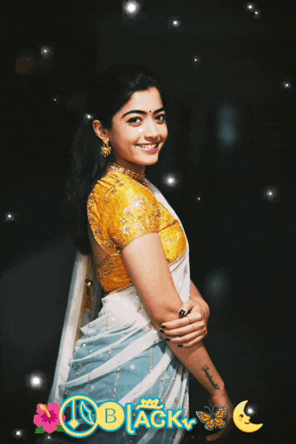 a woman in a white and blue saree is smiling in front of a black background
