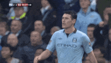 a soccer player wearing a light blue etihad jersey