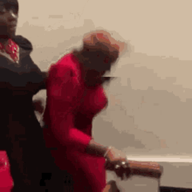 a woman in a red dress is being pushed by a man .