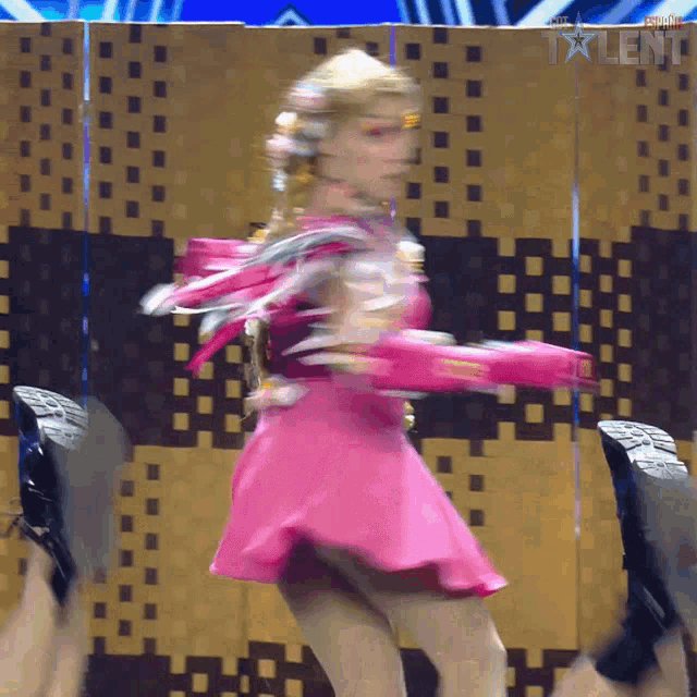 a woman in a pink dress is dancing in front of a wall that says talent on it