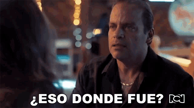 a man in a black shirt is talking to a woman in a restaurant and says eso donde fue .
