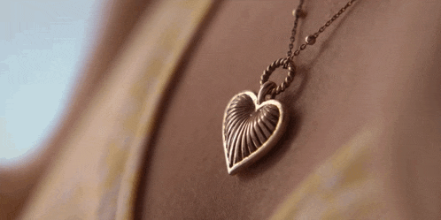 a close up of a person wearing a heart shaped necklace .