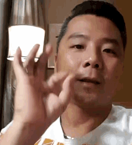 a man in a white shirt is making a funny face with his hands in front of his face .