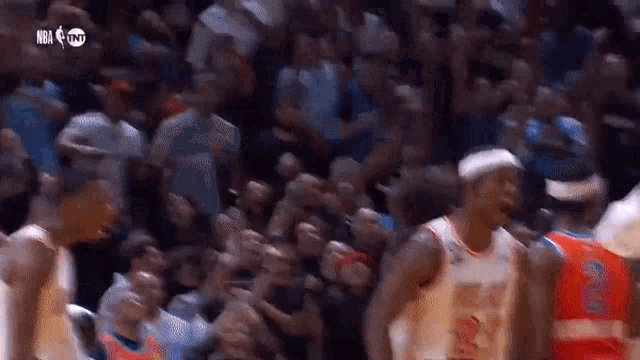 a basketball player is talking to another player in front of a crowd .