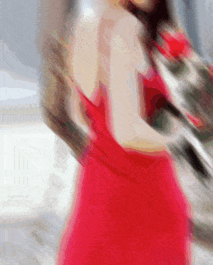 a blurry picture of a woman in a red dress holding a bouquet of roses