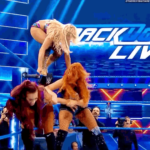 a group of women are wrestling in a ring with a sign that says ' ack live ' on it .